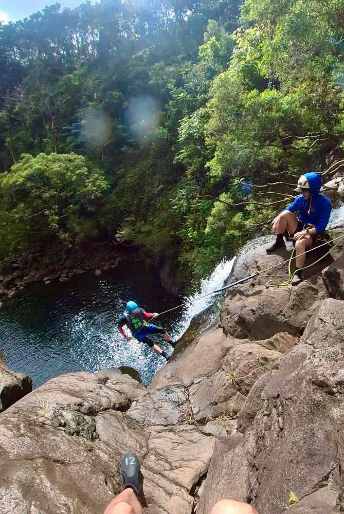 a man rappeling down a waterfall